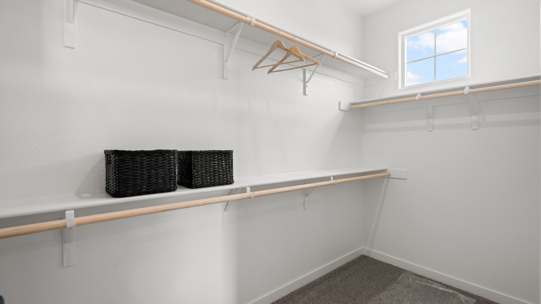 A white room with a shelf and a basket on the wall.