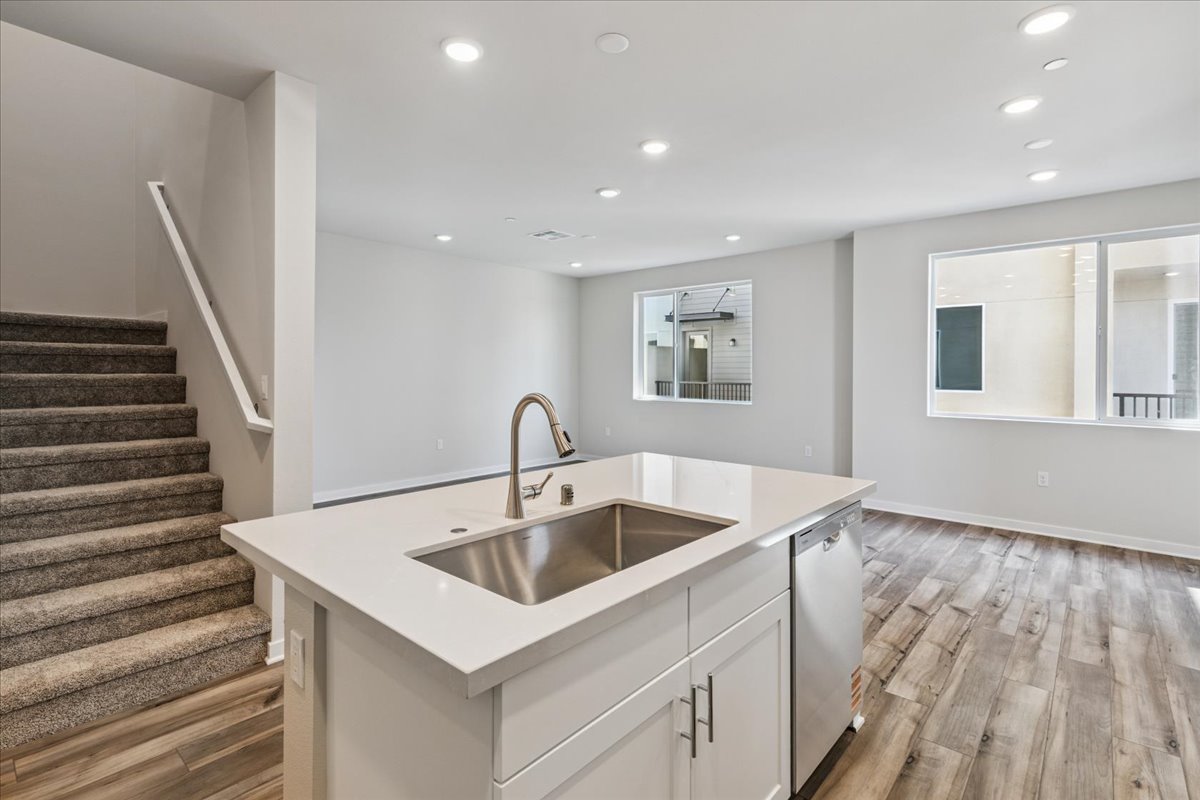 A kitchen with a sink and a staircase.