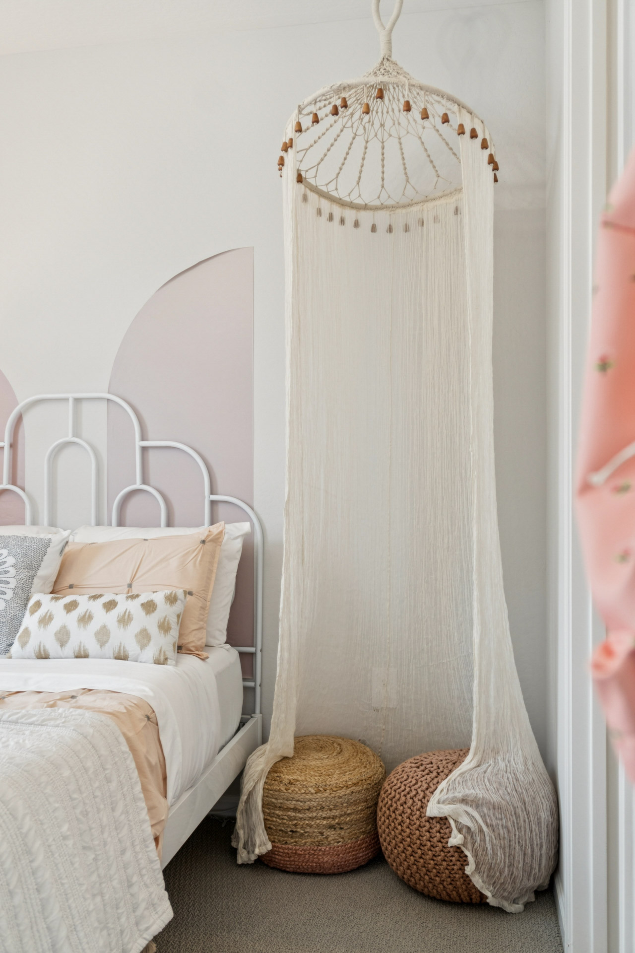 A white crib with a white cloth from it.