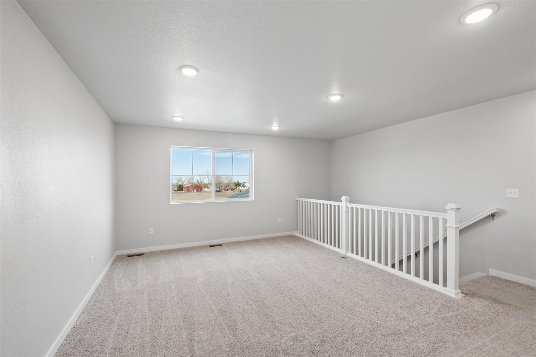 A room with a white railing and a window.
