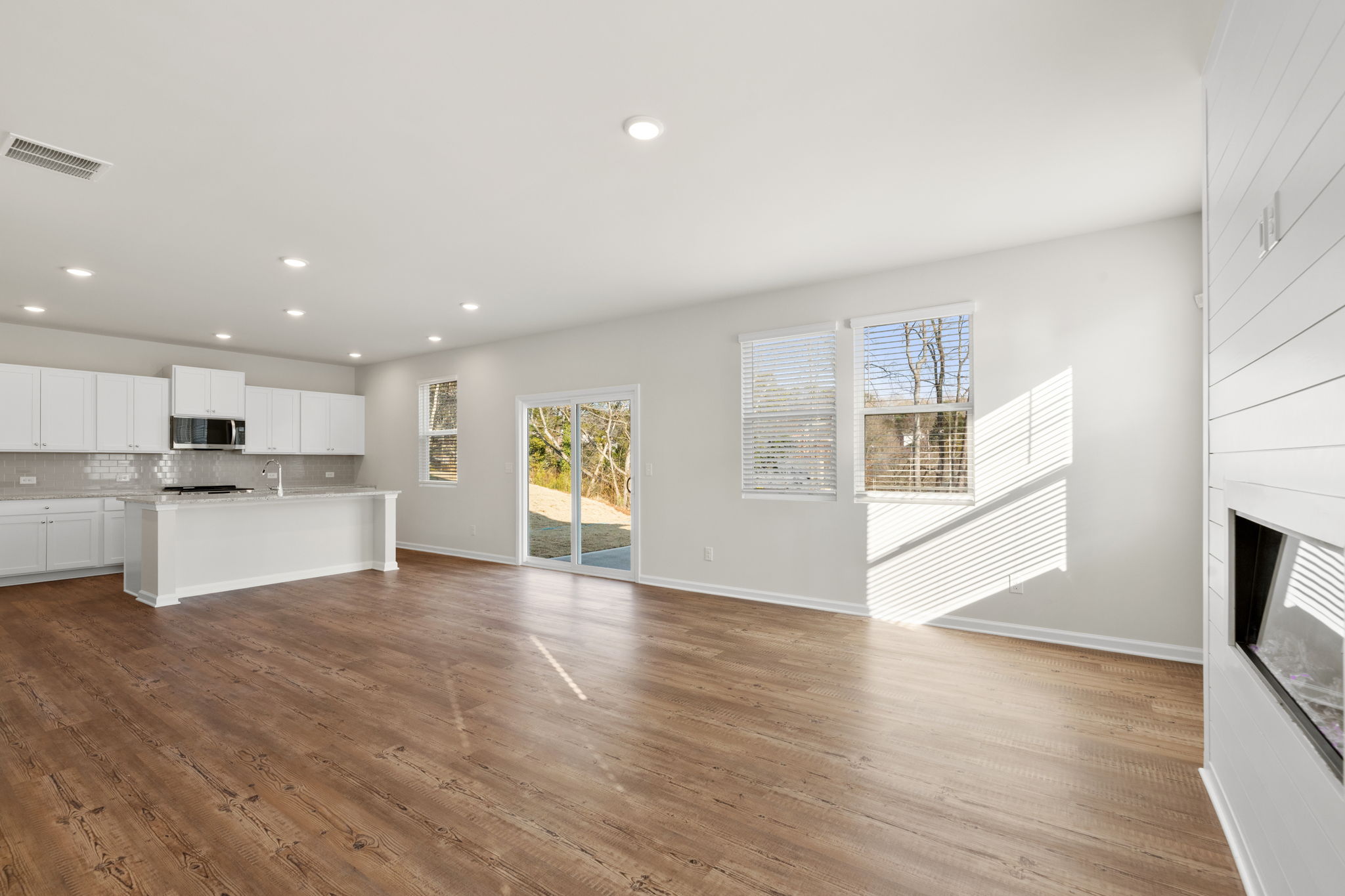 A large white kitchen with a wood floor.