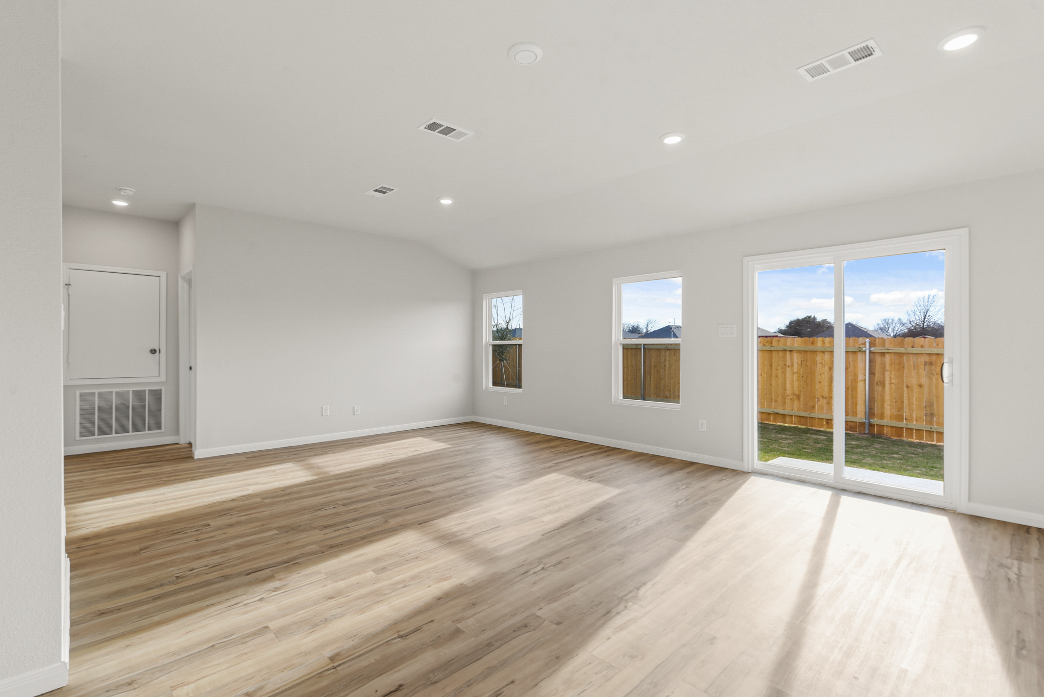 A room with a wood floor and windows.