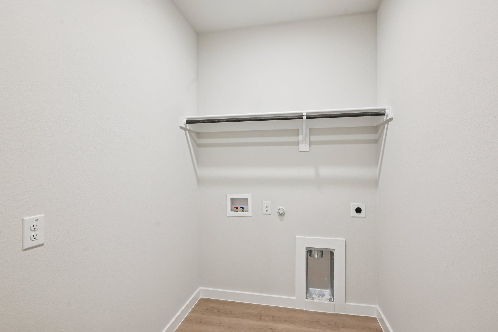 A white room with a wood floor and a metal bar.