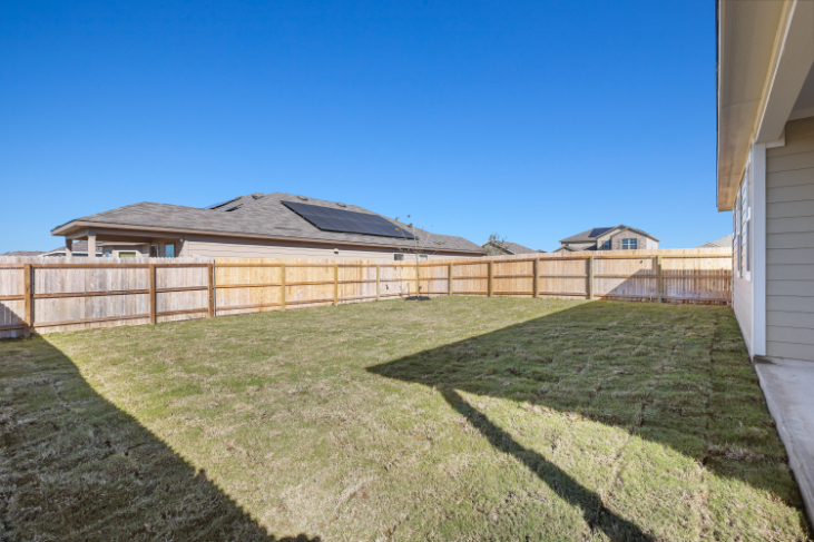 A fenced in yard with a house in the background.
