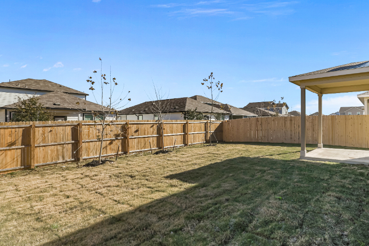 A fenced in yard with a wood fence and a tree.