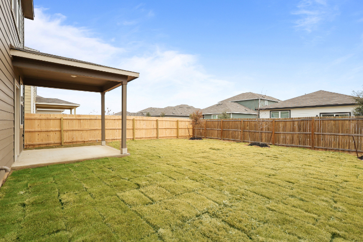 A fenced in yard with a house and trees in the background.