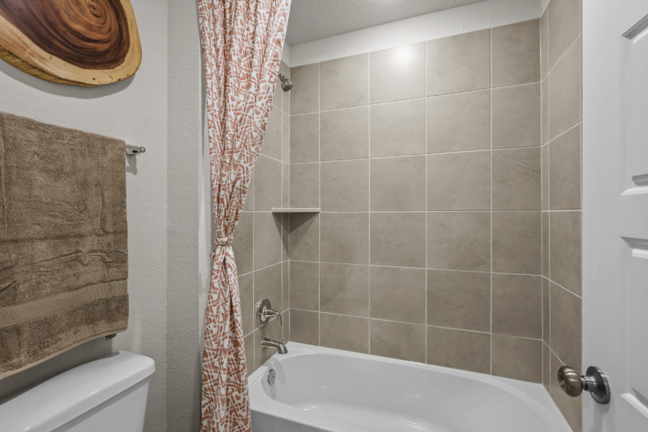 A bathroom with a bathtub and shower curtain.
