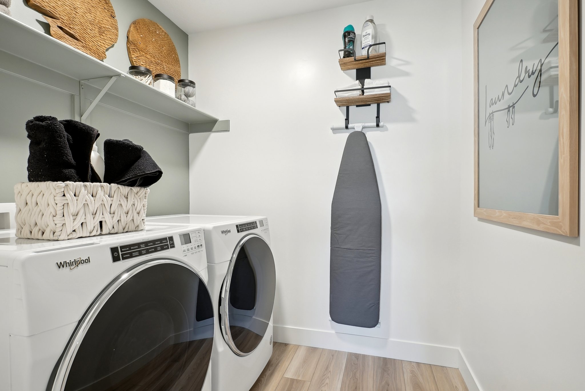 A white laundry room with a shelf and a basket with clothes on it.