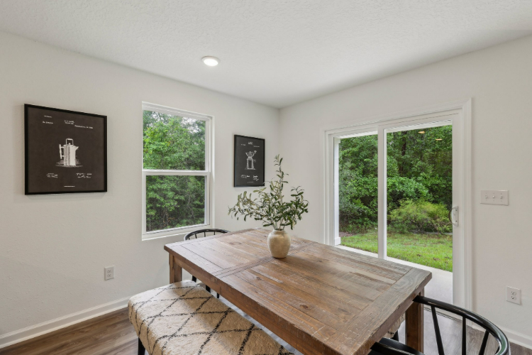 A table with a vase of flowers on it in a room with windows.